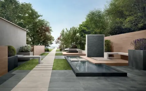 Un elegante giardino con pavimentazione senza cemento, sentiero in pietra, piscina e zona relax.