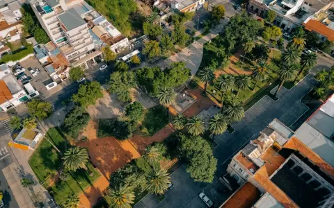 Vista aerea di un parco urbano con palme e alberi, circondato da edifici. Un esempio di come la legge sulla rigenerazione urbana possa trasformare spazi verdi in città.