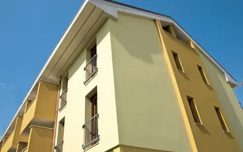 Edificio moderno con facciata bicolore, protetta da vernice isolante termica Mapei, sotto un cielo azzurro.