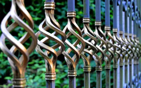 Dettaglio di una ringhiera in ferro battuto con decorazioni a spirale dorate, pronta per essere sverniciare.