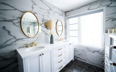 Bagno moderno con marmo, doppio lavabo e rubinetteria oro. Un'idea per capire quanto costa piastrellare un bagno di 5 mq.