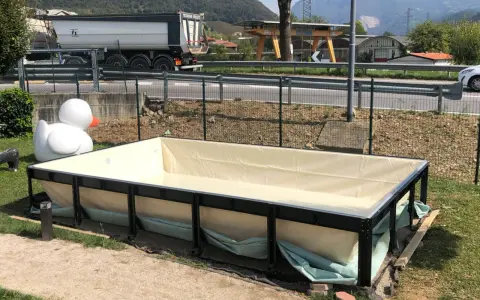 Piscina seminterrata in fase di installazione, con un grande anatroccolo gonfiabile sullo sfondo. Si attendono i permessi per completare il progetto.