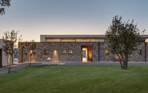 Villetta moderna in pietra, con prato curato e alberi. Un esempio di come potrebbe essere quanto costa costruire una villetta di 120 mq.