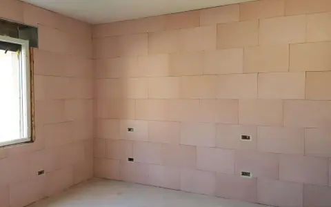 Pannelli rosa per cappotto interno con lana di roccia e cartongesso, con predisposizioni per prese elettriche e una finestra.