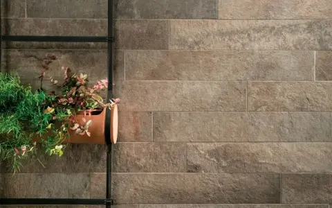 Un muro esterno rivestito con lastre effetto pietra, con un vaso di piante appeso. Ottime idee per coprire muro esterno con stile naturale.