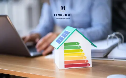 Modello di casa con pannelli solari e scala di efficienza energetica. La migliore immobiliare valuta la classe energetica casa.