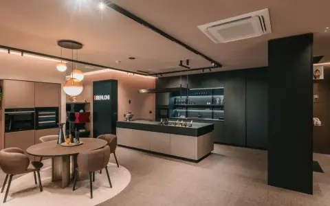 Elegante cucina scura con isola centrale e un tavolo rotondo. Il pavimento chiaro crea un contrasto moderno e luminoso.