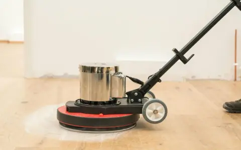 Macchina levigatrice in azione per levigare parquet fai da te. La polvere bianca indica il lavoro in corso.