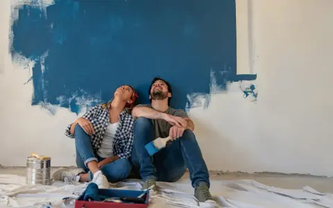 Coppia seduta sul pavimento, guarda in alto verso un muro dipinto di blu. Stacco tra parete e soffitto si o no?