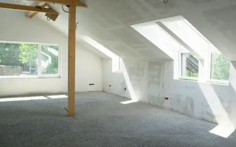 Sottotetto in costruzione con pareti in cartongesso e un pavimento in materiale granulare, pronto per essere calpestabile.