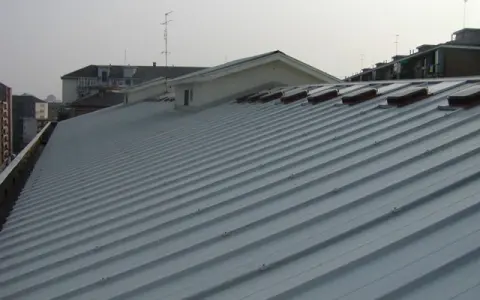 Tetto moderno rifatto con pannelli coibentati grigi, con lucernari a vista.