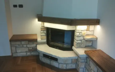 Un camino rustico in pietra e legno, con panche integrate. Un esempio di come costruire un camino rustico che unisce funzionalità ed estetica.