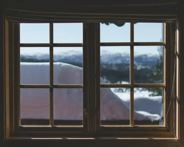 Finestra con infissi in legno, vista su paesaggio innevato. Ideale per chi vuole rinnovare infissi in legno fai da te.