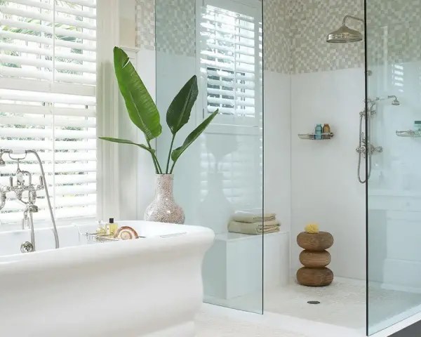 Bagno elegante con vasca freestanding e doccia con ampie dimensioni. Piante verdi e dettagli in mosaico completano l'ambiente.