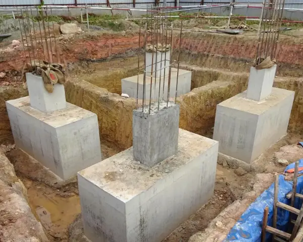 Scavi per il consolidamento fondazioni con pilastri in cemento armato e armature in vista.