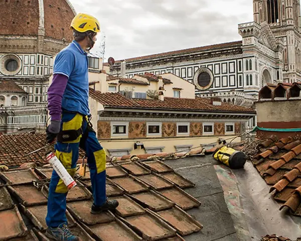 Operaio sul tetto di Firenze, valuta il costo coibentazione tetto esistente. Lavori in quota con vista Duomo.