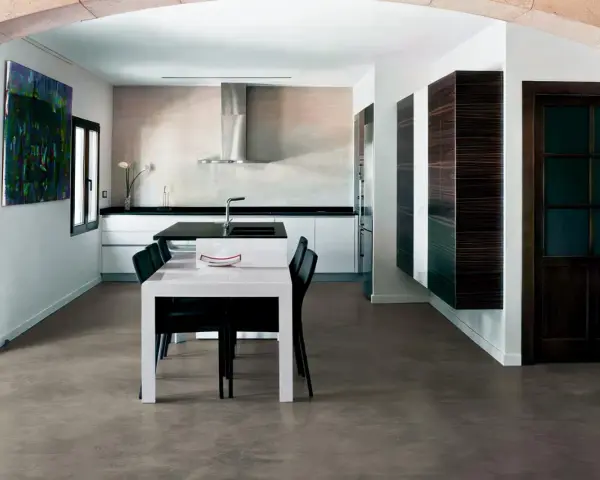 Modern kitchen with a dining area. The **pavimento in cemento per interni costi** is visible, offering a sleek and contemporary look.