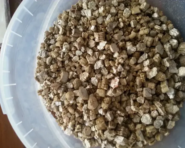 Granuli di vermiculite espansa isolante termico in un secchio bianco. Materiale leggero e poroso, ideale per l'edilizia.