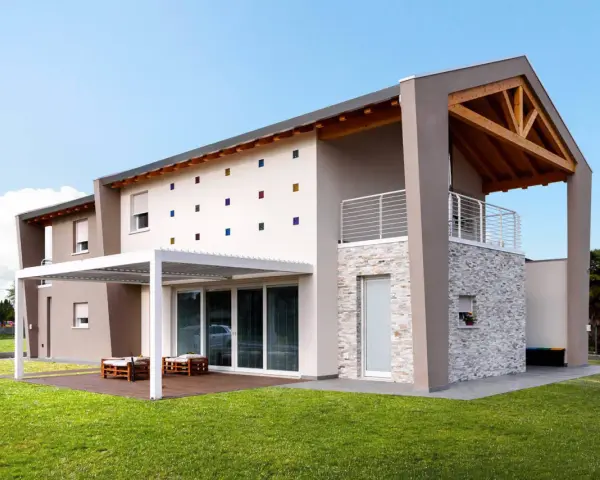 Casa moderna con tetto in legno a vista, facciata decorata con quadrati colorati e un portico bianco.