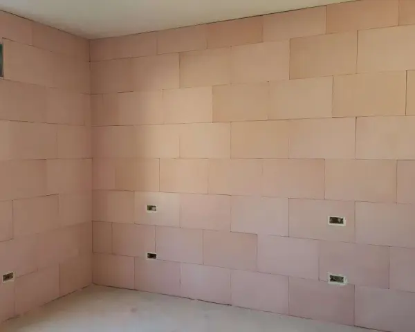 Pannelli rosa per cappotto interno con lana di roccia e cartongesso, con predisposizioni per prese elettriche e una finestra.
