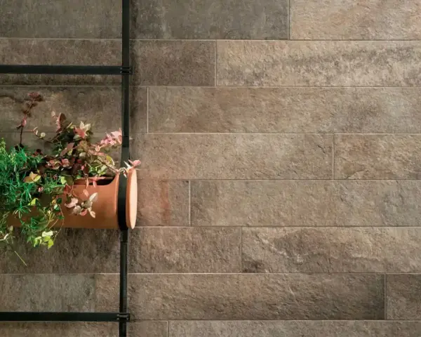 Un muro esterno rivestito con lastre effetto pietra, con un vaso di piante appeso. Ottime idee per coprire muro esterno con stile naturale.