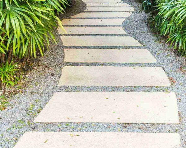 Un sentiero sinuoso con lastre di pietra e ghiaia, circondato da vegetazione lussureggiante. Idee marciapiede casa per un ingresso accogliente.
