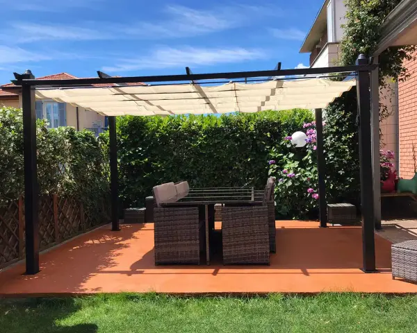 Un patio con tavolo e sedie sotto una pergola, con un **pavimento esterno economico fai da te** color terracotta.