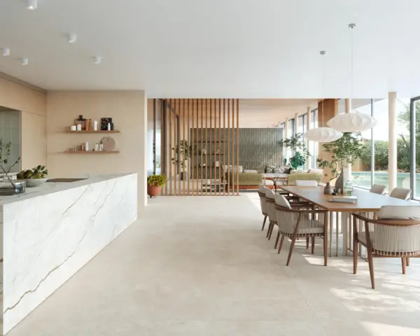 Ampio open space con cucina moderna, isola in marmo e zona pranzo. Pavimenti diversi creano continuità visiva tra gli ambienti.