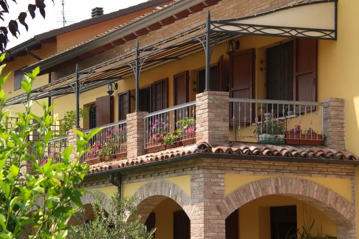 Il montaggio scossalina balcone protegge la facciata. Balcone fiorito con ringhiera in ferro battuto e tettoia decorata.