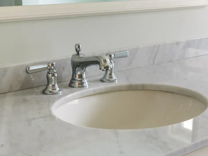 Lavandino in marmo poroso con rubinetteria cromata. Per sapere come pulire il marmo poroso, guarda questo bagno elegante.