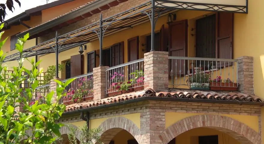Il montaggio scossalina balcone protegge la facciata. Balcone fiorito con ringhiera in ferro battuto e tettoia decorata.