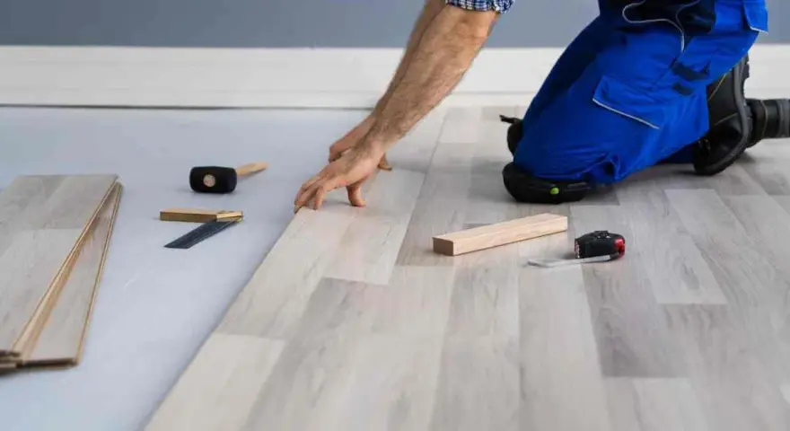 Installazione di un nuovo pavimento in laminato, un passo fondamentale per come isolare il pavimento dal freddo. Attrezzi da lavoro a portata di mano.