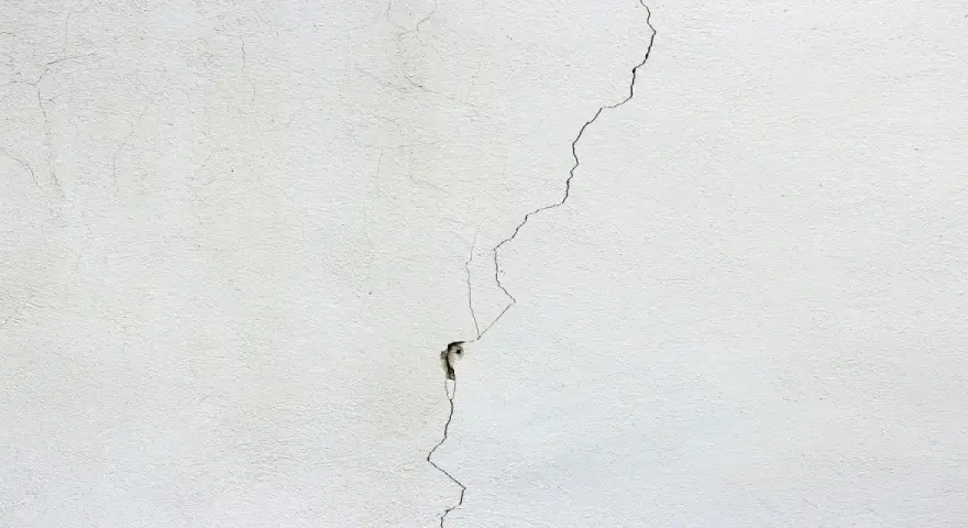 Crepa profonda su muro bianco, un segno per come distinguere le crepe pericolose.