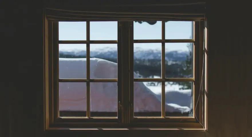 Finestra con infissi in legno, vista su paesaggio innevato. Ideale per chi vuole rinnovare infissi in legno fai da te.