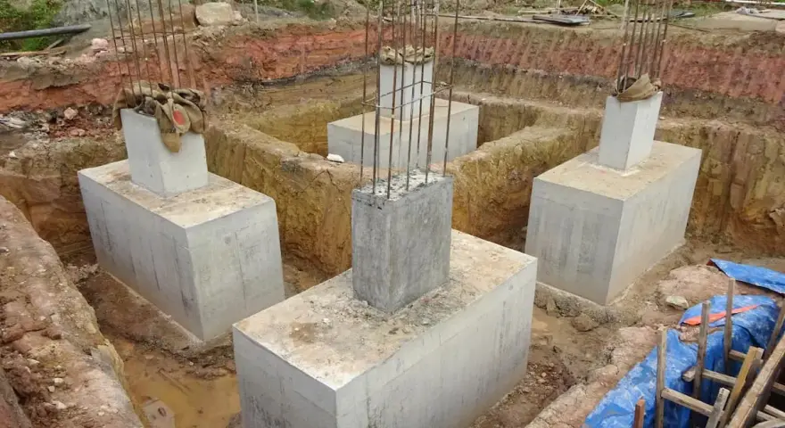 Scavi per il consolidamento fondazioni con pilastri in cemento armato e armature in vista.