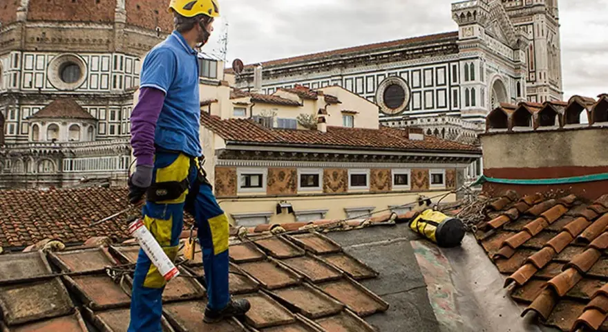 Operaio sul tetto di Firenze, valuta il costo coibentazione tetto esistente. Lavori in quota con vista Duomo.