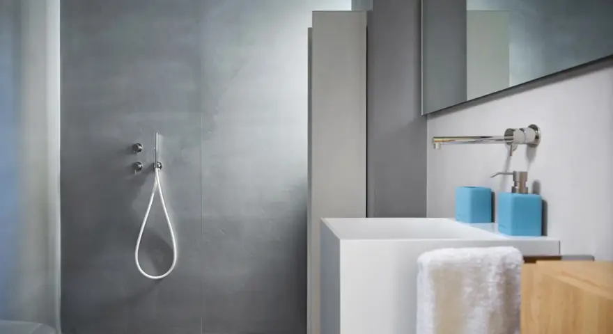 Bagno moderno con rivestimento doccia senza piastrelle effetto resina, lavabo bianco e accessori azzurri.
