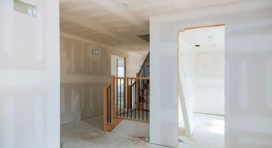 Interni in fase di finitura, con pareti pronte per essere rivestite con cartongesso senza telaio. Scala in legno e metallo.
