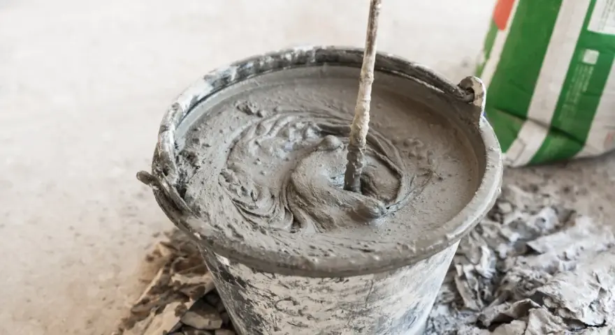 Secchio con malta fresca in preparazione, mostrando la differenza tra malta e cemento. Un sacco di cemento è visibile sullo sfondo.