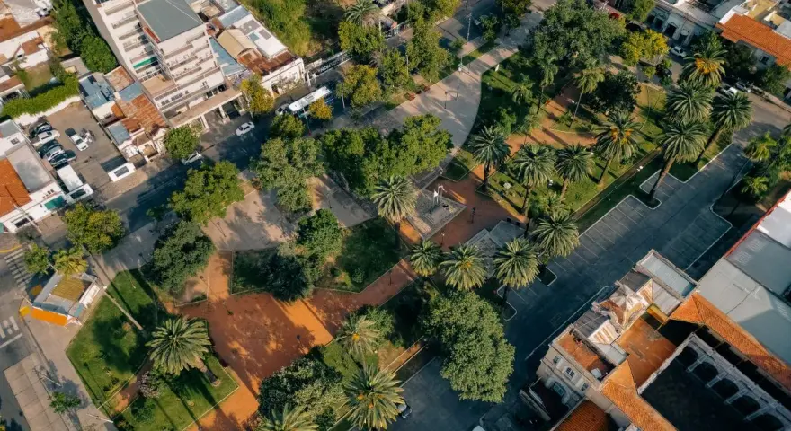 Vista aerea di un parco urbano con palme e alberi, circondato da edifici. Un esempio di come la legge sulla rigenerazione urbana possa trasformare spazi verdi in città.