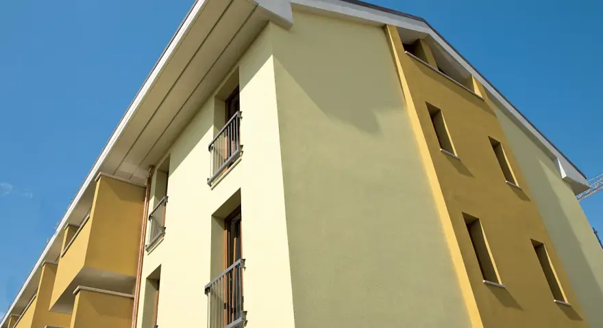 Edificio moderno con facciata bicolore, protetta da vernice isolante termica Mapei, sotto un cielo azzurro.
