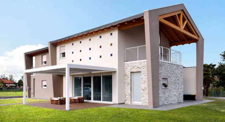 Casa moderna con tetto in legno a vista, facciata decorata con quadrati colorati e un portico bianco.