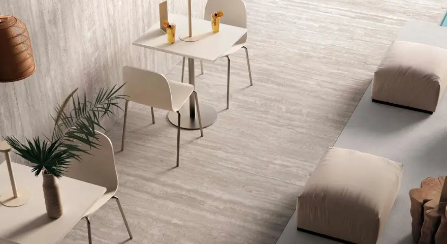 Un caffè moderno con tavolini, sedie e pouf, su eleganti pavimenti senza fughe effetto pietra.