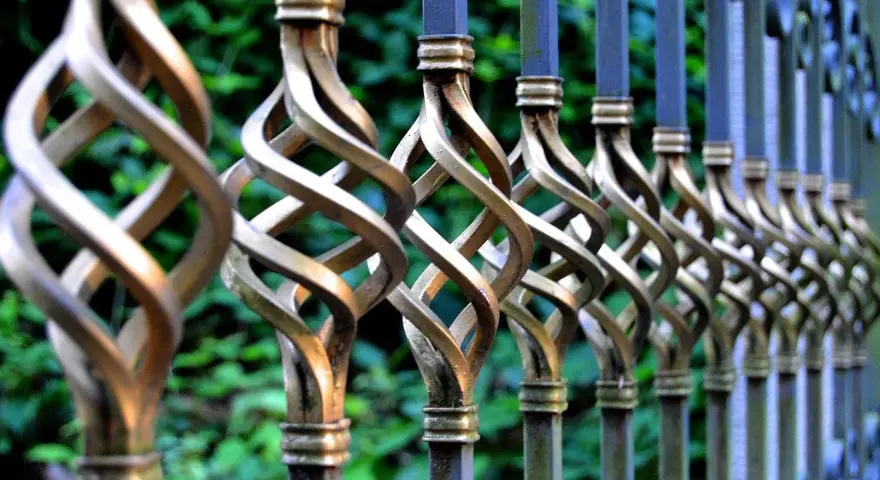 Dettaglio di una ringhiera in ferro battuto con decorazioni a spirale dorate, pronta per essere sverniciare.