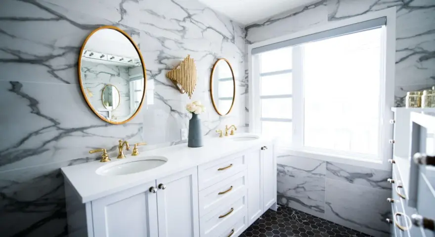Bagno moderno con marmo, doppio lavabo e rubinetteria oro. Un'idea per capire quanto costa piastrellare un bagno di 5 mq.
