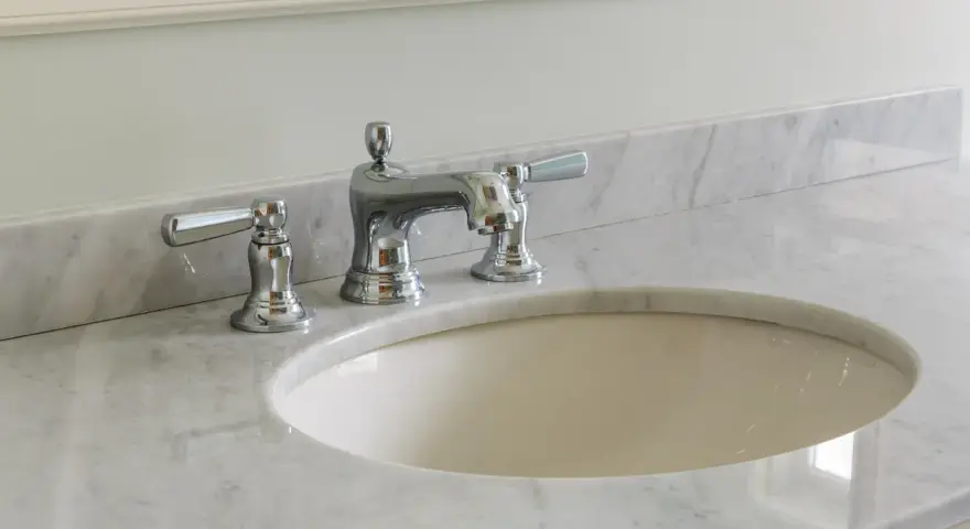 Lavandino in marmo poroso con rubinetteria cromata. Per sapere come pulire il marmo poroso, guarda questo bagno elegante.