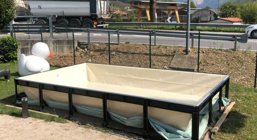 Piscina seminterrata in fase di installazione, con un grande anatroccolo gonfiabile sullo sfondo. Si attendono i permessi per completare il progetto.