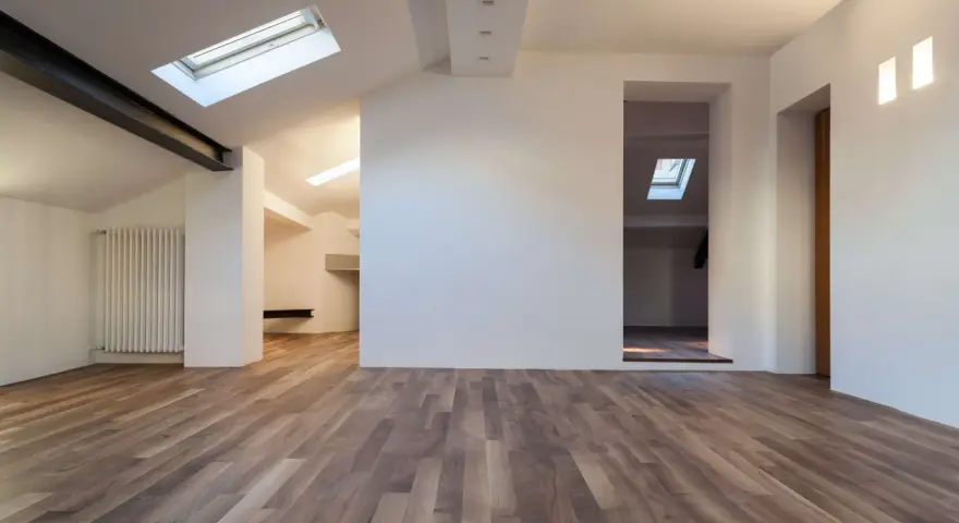 Interno moderno con pavimenti in legno e pareti in cartongesso sottotetto. Finestre sul tetto illuminano lo spazio.