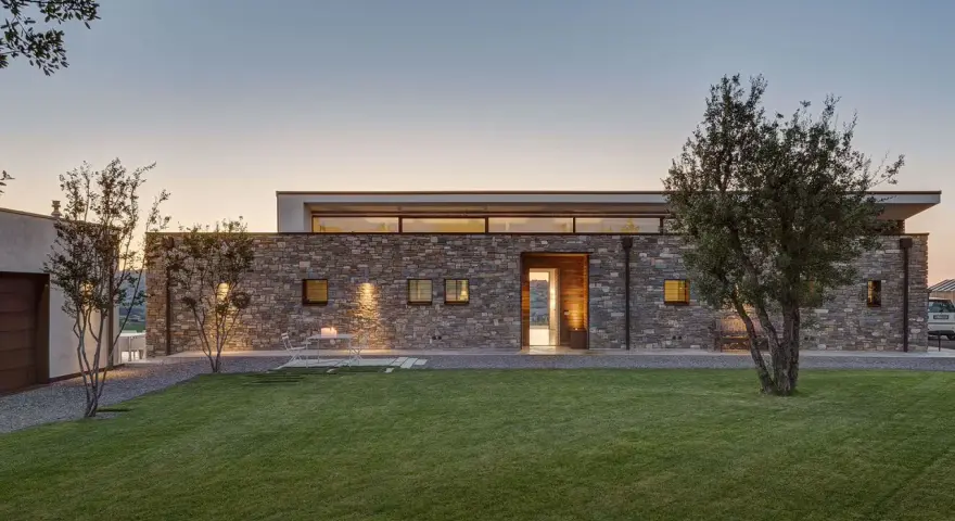 Villetta moderna in pietra, con prato curato e alberi. Un esempio di come potrebbe essere quanto costa costruire una villetta di 120 mq.