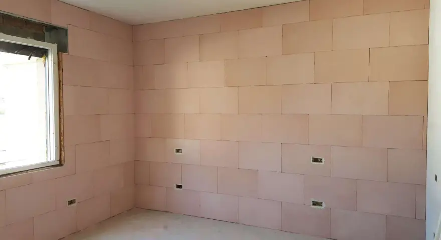 Pannelli rosa per cappotto interno con lana di roccia e cartongesso, con predisposizioni per prese elettriche e una finestra.